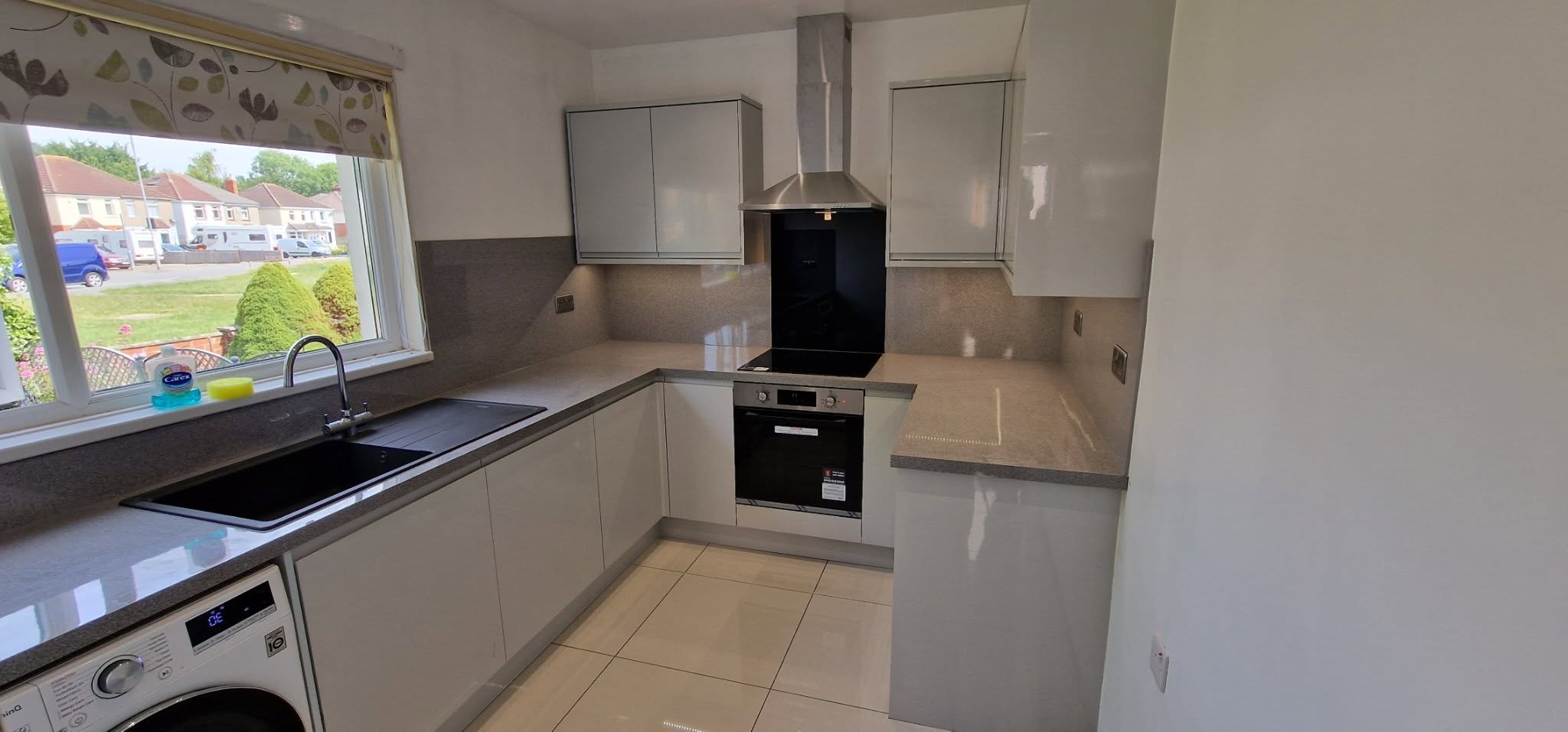 Completed Howdens Clerkenwell Gloss Dove Grey kitchen with Light Grey Mirror Chip worktops and matching backboards