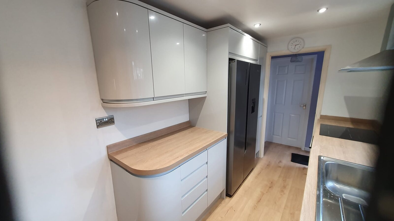 Completed storage side with curved Gloss Dove Grey units and oak-effect worktop