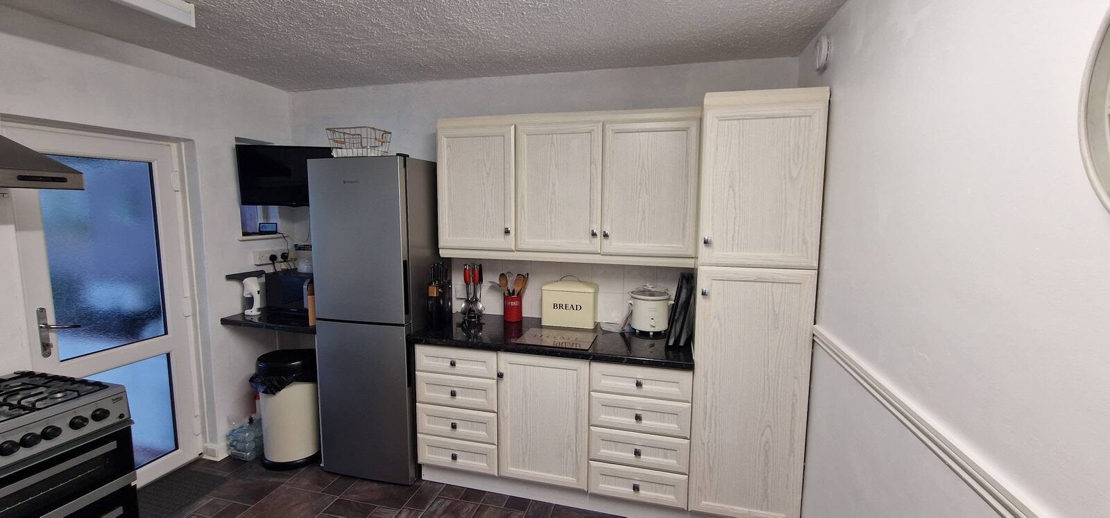 Older white kitchen before its grey gloss transformation, storage wall